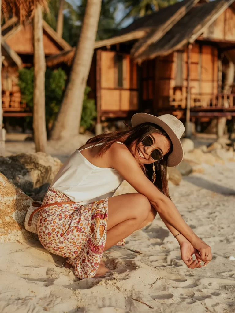 Smiling woman at a Phuket beach bungalow at golden hour.