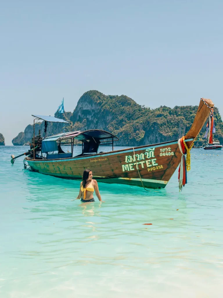 Long-tail boat and swimmer in turquoise water near Phuket