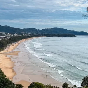 Wide karon beach coastline phuket landscape showing waves, sand, and distant hills.