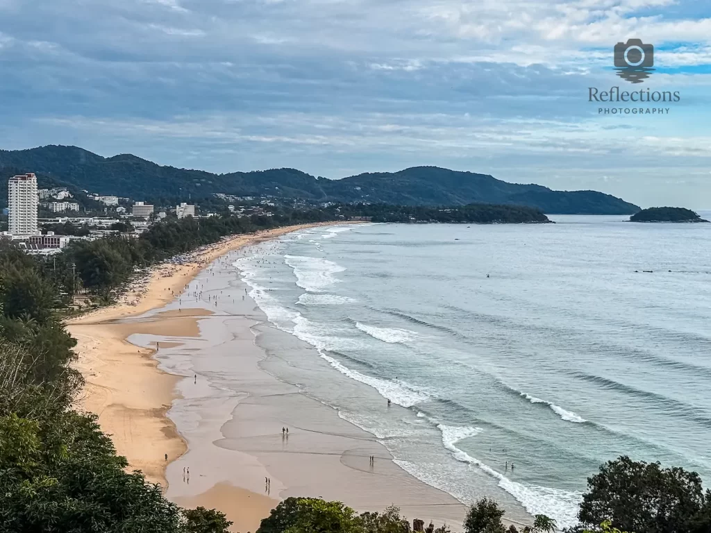Wide coastal view of Karon Beach in Phuket, Thailand, with waves, sand and distant hills – example of a real scene used for Reflections Photography Field Guides.
