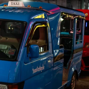 A blue tuk tuk taxi patong nightlife scene showing colourful vehicles parked along a busy street at night in Phuket.