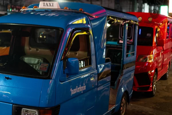 A blue tuk tuk taxi patong nightlife scene showing colourful vehicles parked along a busy street at night in Phuket.