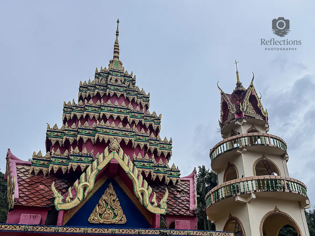 Ubosot gate roof and bell tower at Wat Suwan Khiri Wong Patong showing layered temple architecture and elevation