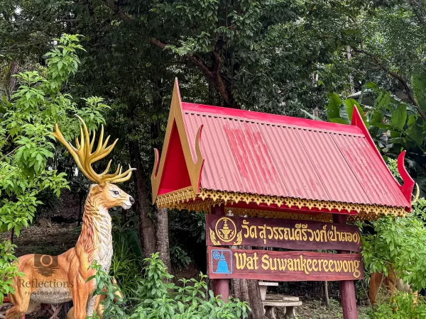 wat suwan khirri wong entrance sign with golden deer statue and red roof shelter