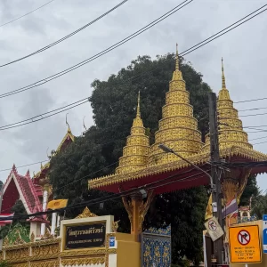 main gate wat suwan khirri wong with golden spires and roadside temple entrance