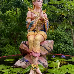 praying deity statue wat suwan khirri wong seated above lotus pond with tropical foliage