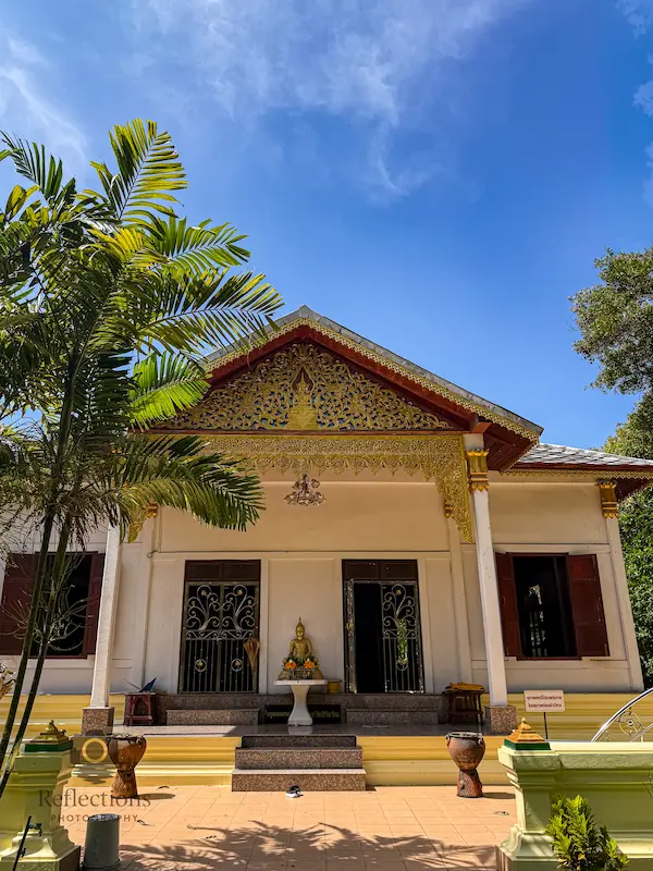 Upper temple building at Wat Suwan Khiri Wong Patong with simple façade, offering table, and calm midday light