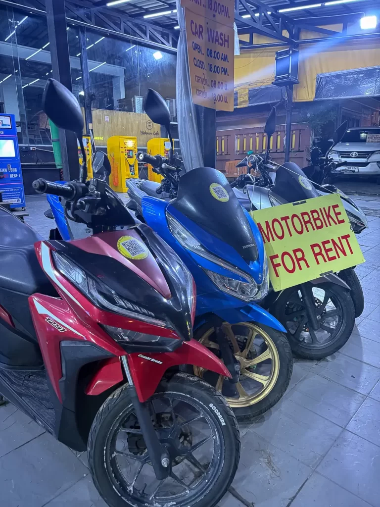 A crowded night street photo with multiple motorbikes and competing signs