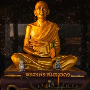 golden monk statue wat suwan khirri wong seated in meditation with offerings
