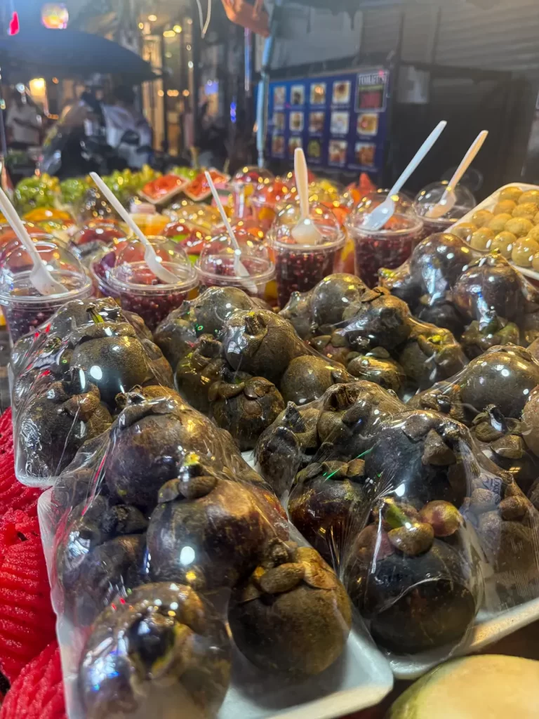 Street market photo where the fruit in the foreground becomes the first point of attention instead of the lights above.