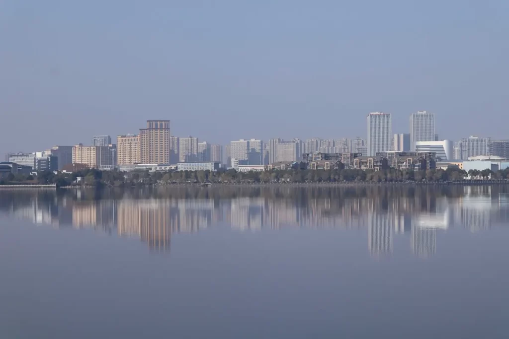 Soft city skyline reflection creating atmosphere and emotional calm through still water in travel photography.