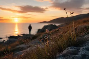Person standing quietly on a rocky coastline at sunset demonstrating timing, atmosphere, and observation in photography