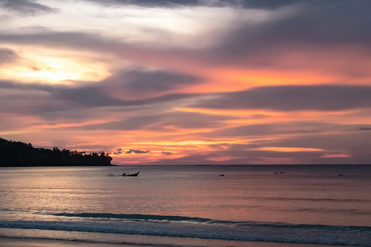 Small boat moving across calm water beneath a colourful dusk sky, illustrating atmosphere in photography through light, colour, and environmental mood.